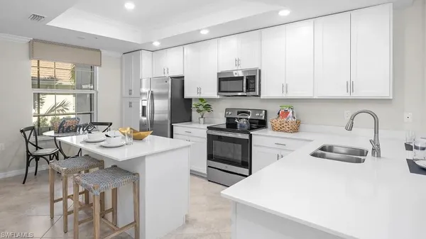 a kitchen with stainless steel appliances a sink a stove a refrigerator cabinets and a dining table with wooden floor