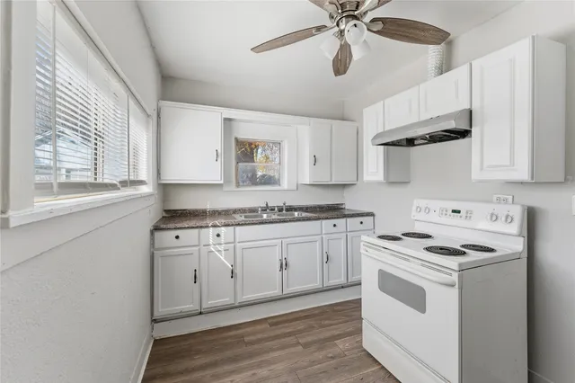 a kitchen with stainless steel appliances granite countertop white cabinets a sink a stove and a refrigerator