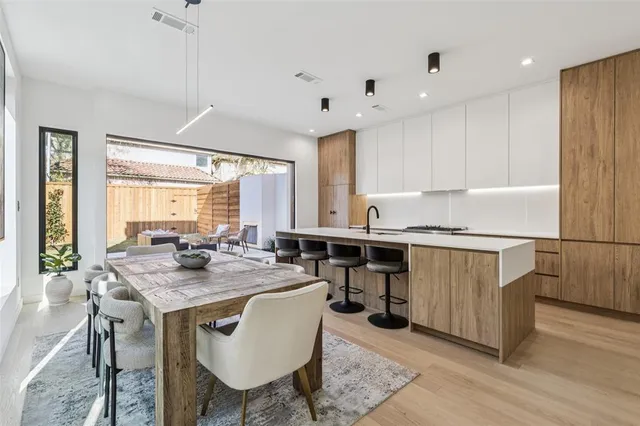 a kitchen with stainless steel appliances granite countertop a stove a sink a refrigerator and chairs