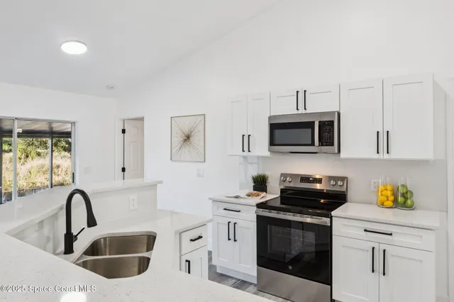 a kitchen with stainless steel appliances granite countertop a sink a stove a microwave a refrigerator a counter space and cabinets