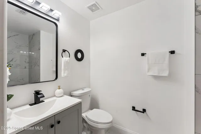 a bathroom with a sink vanity mirror and toilet