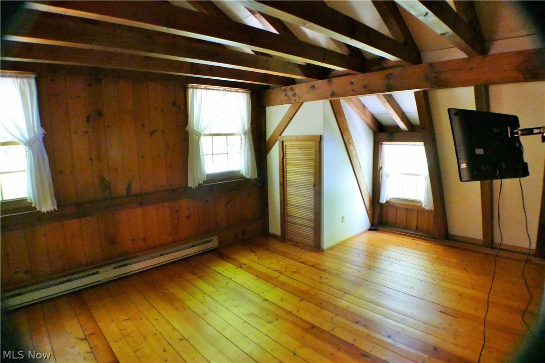 17340 Huntley Road Huntsburg, OH 44046 - Photo 17 of 24 Unfurnished room featuring a wealth of natural light, vaulted ceiling with beams, and light wood-type flooring