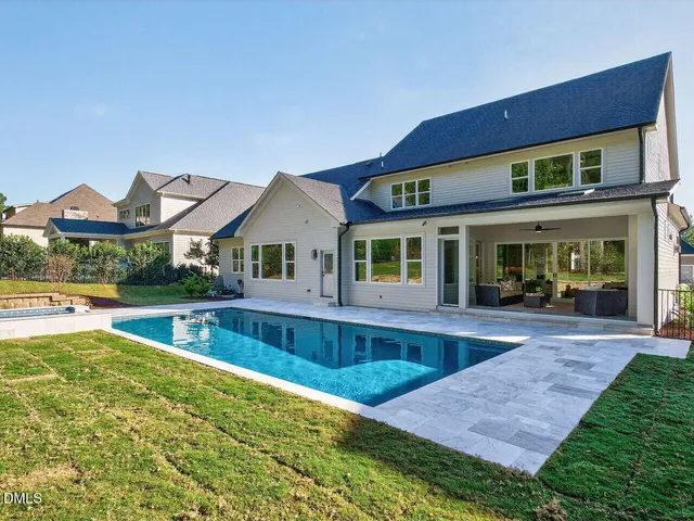 a view of house with swimming pool and a yard