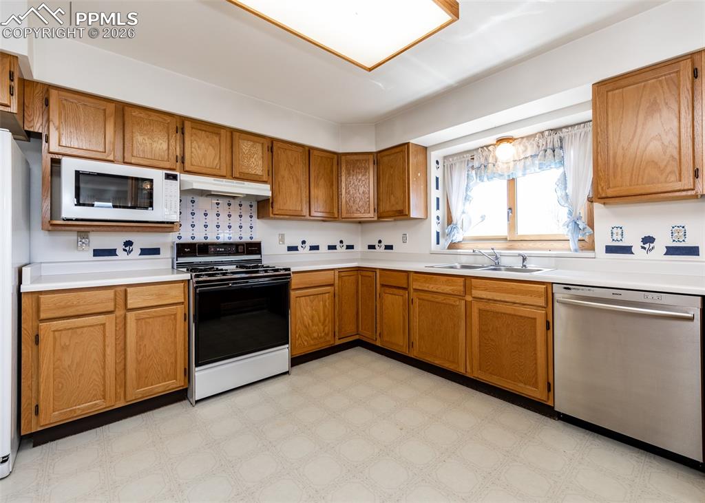 6185 Sayres Road Colorado Springs, CO 80927 - Photo 15 of 50 a kitchen with stainless steel appliances granite countertop a sink a stove a refrigerator cabinets and a window