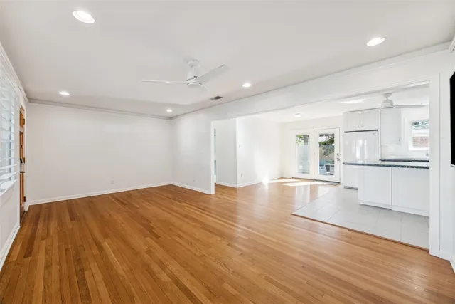 a view of empty room with wooden floor and kitchen