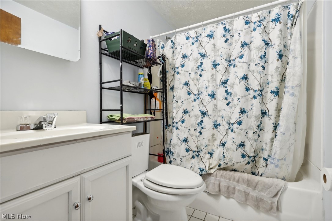 16146 Ravenna Road Burton, OH 44021 - Photo 17 of 27 Full bathroom with shower / bathtub combination with curtain, toilet, tile flooring, vanity, and a textured ceiling