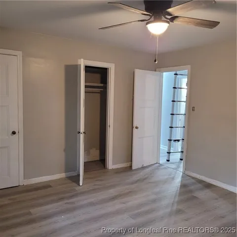 an empty room with wooden floor chandelier fan and closet area