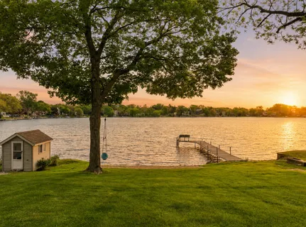a lake view with a big yard and large trees