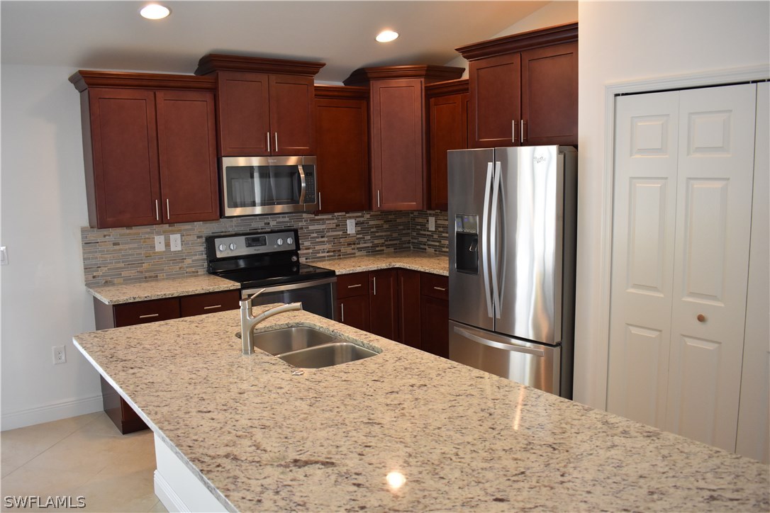 8152 Anhinga Road Fort Myers, FL 33967 - Photo 8 of 19 a kitchen with kitchen island a refrigerator sink and stove