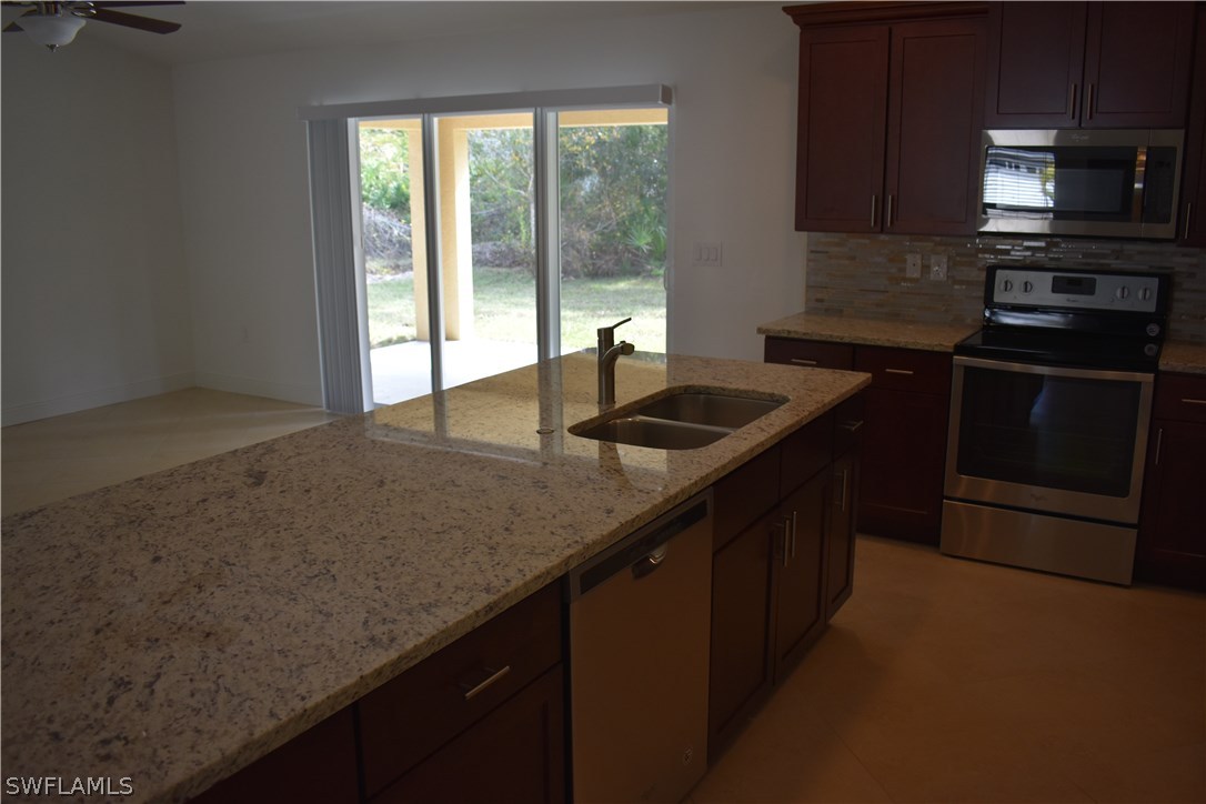 8152 Anhinga Road Fort Myers, FL 33967 - Photo 9 of 19 a kitchen with kitchen island granite countertop a sink and a stove
