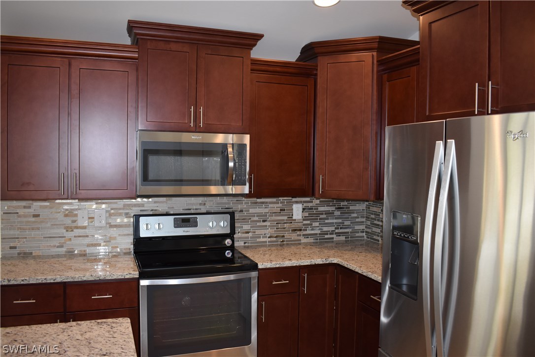 8152 Anhinga Road Fort Myers, FL 33967 - Photo 10 of 19 a kitchen with granite countertop a refrigerator stove and microwave