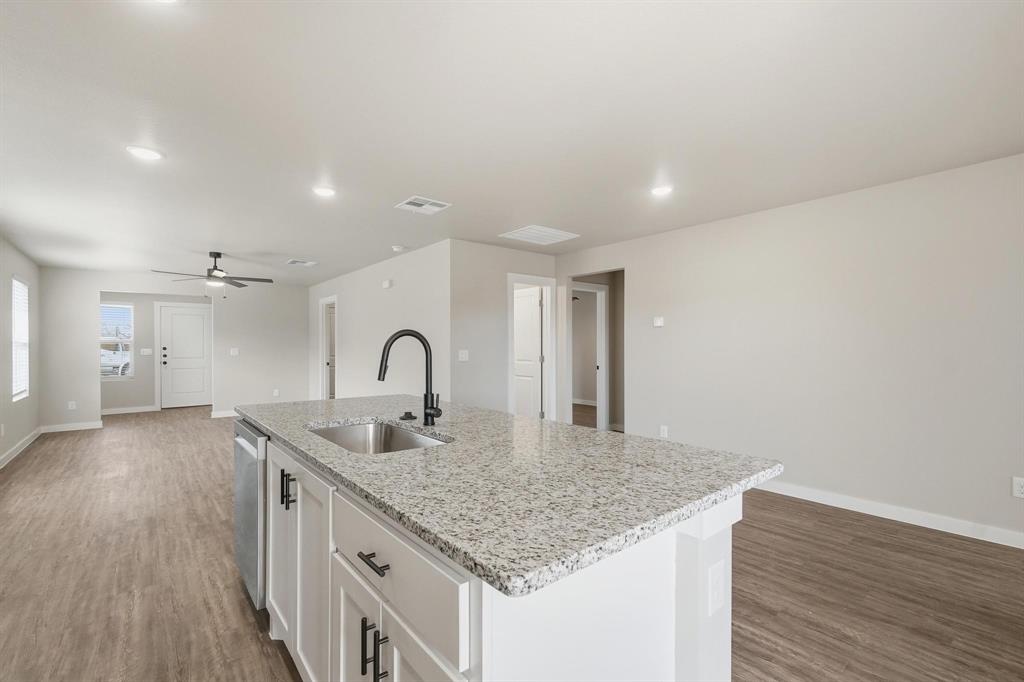 4141 Ranger Road Abilene, TX 79601 - Photo 4 of 10 Kitchen with light wood-style flooring, a center island with sink, light stone countertops, white cabinets, and recessed lighting