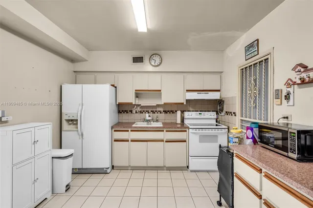 a kitchen with white cabinets and white appliances