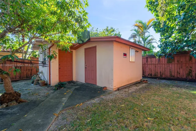 a view of backyard of house with wooden fence and trees