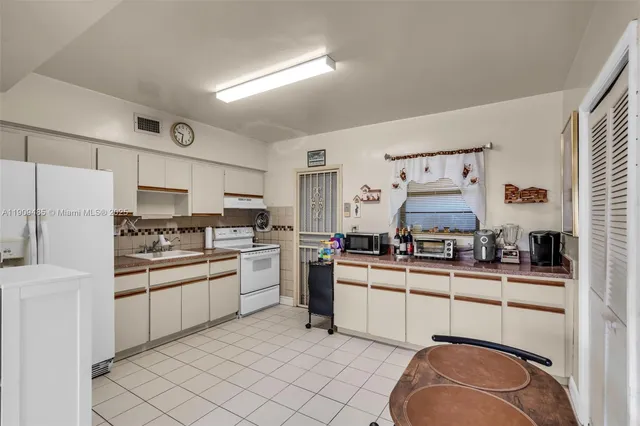 a kitchen with cabinets a sink and white appliances
