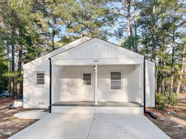 a view of a white house with large windows and a tree