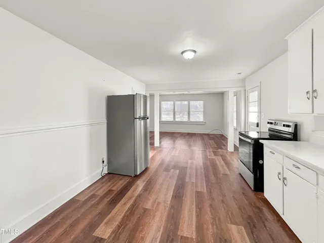 a kitchen with a refrigerator and wooden floor