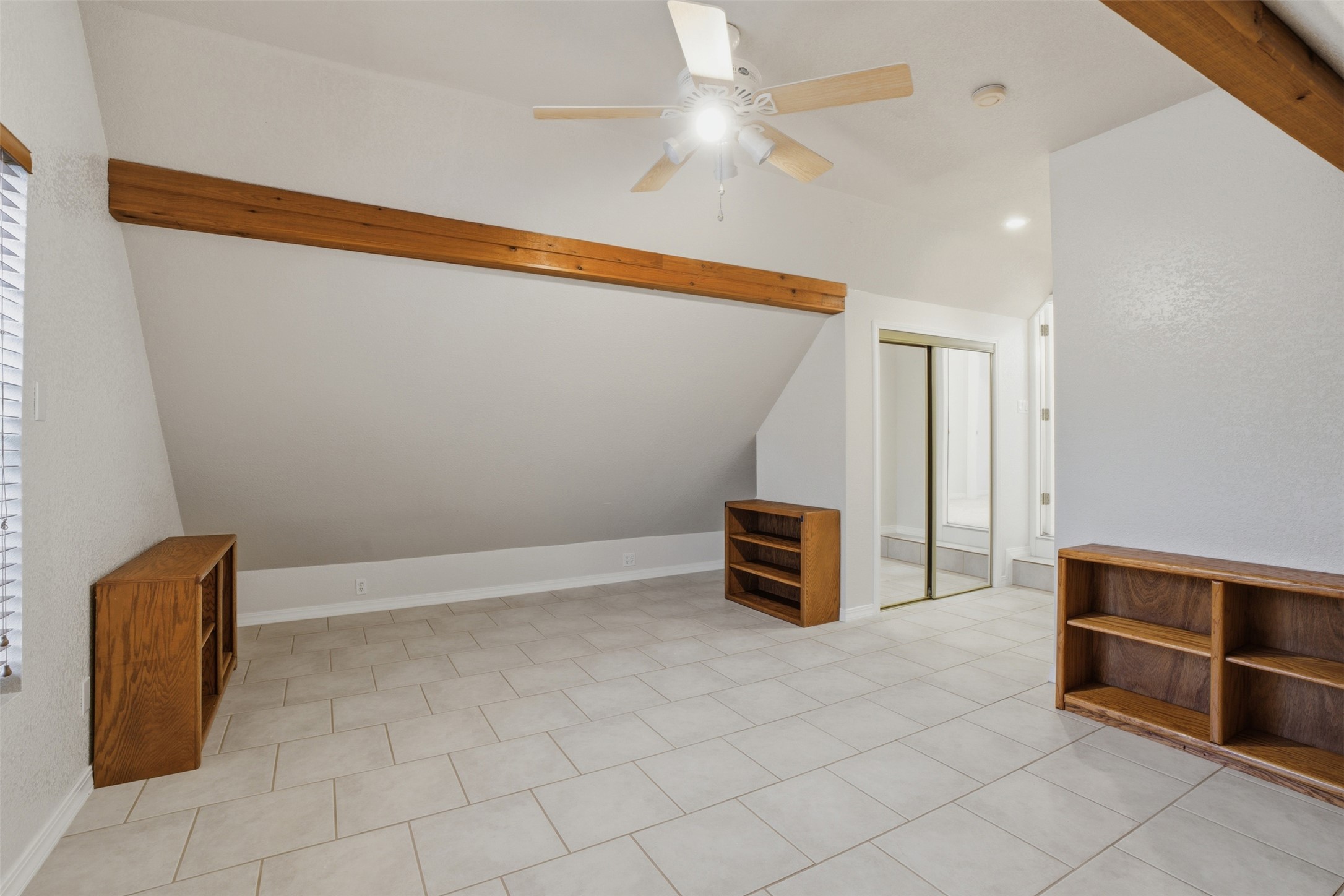 1301 County Road 262 Georgetown, TX 78633 - Photo 26 of 39 Spacious room featuring vaulted ceilings with exposed wood beams, ceiling fan, tile flooring, and mirrored closet doors
