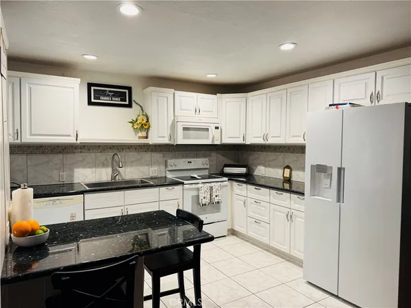 a kitchen with stainless steel appliances a sink a stove a refrigerator cabinets and a window