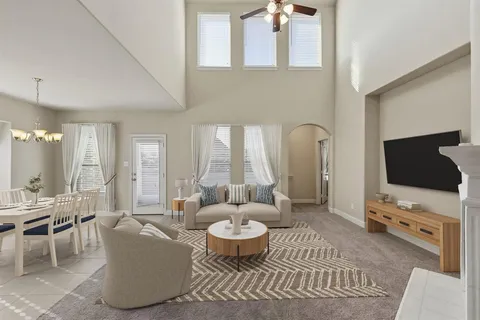 a living room with furniture a flat screen tv and a floor to ceiling window