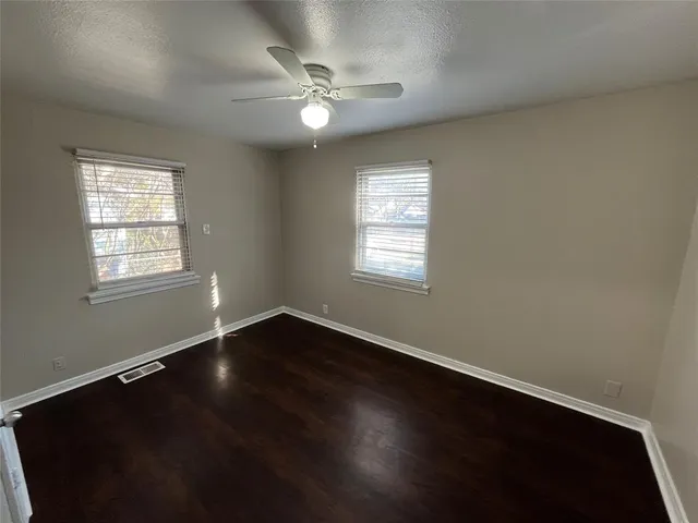 an empty room with wooden floor and fan