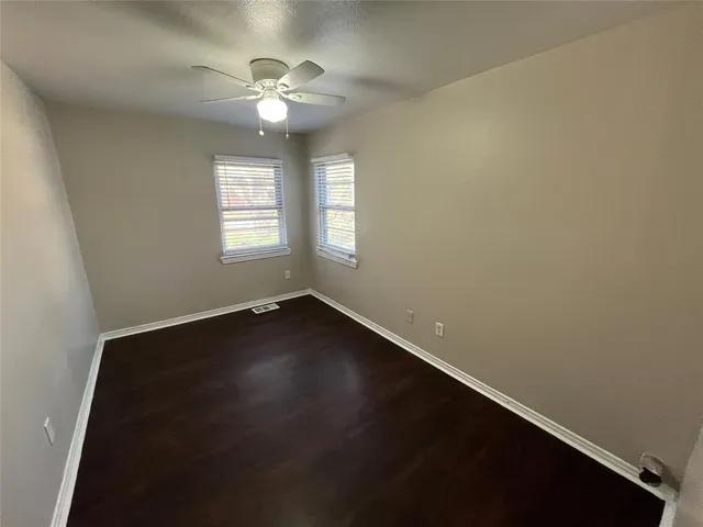 an empty room with wooden floor and fan