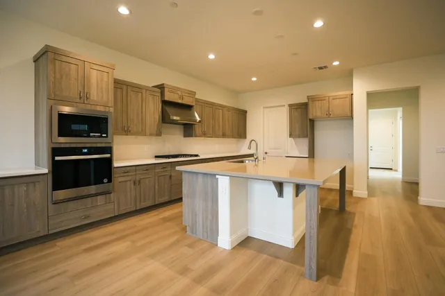 a kitchen with stainless steel appliances a stove a sink a refrigerator and cabinets