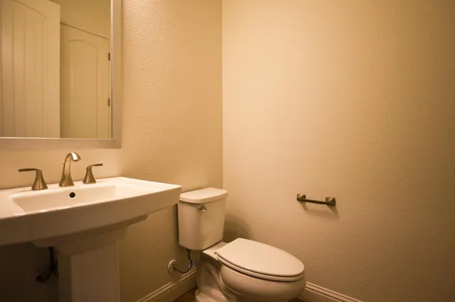 a bathroom with a toilet a sink and mirror