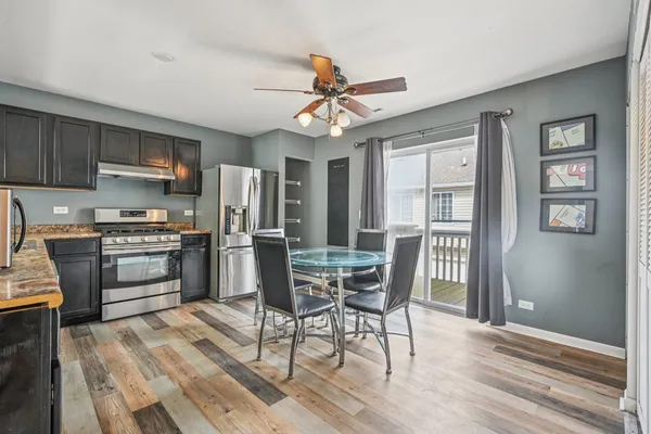 a kitchen with stainless steel appliances a dining table chairs refrigerator and cabinets