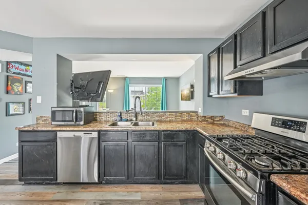 a kitchen with stainless steel appliances granite countertop a sink stove and cabinets