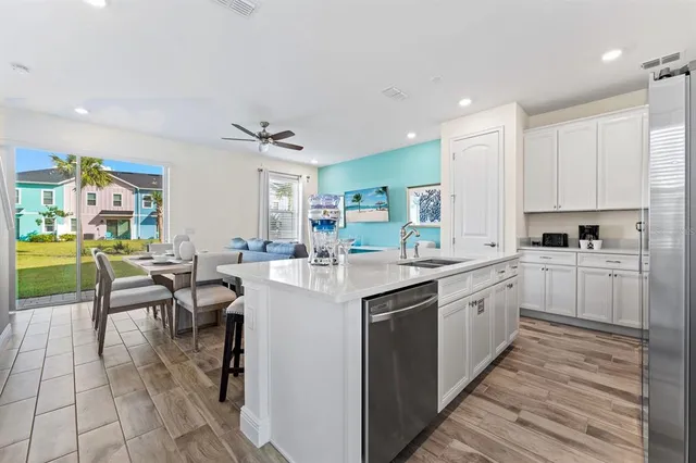a living room with furniture kitchen view and a wooden floor