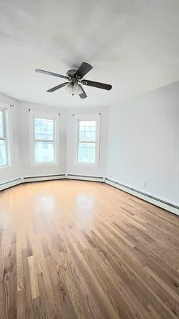 a view of empty room with wooden floor and fan