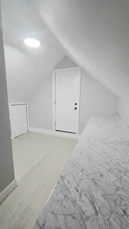 an empty room with wooden floor chandelier and windows