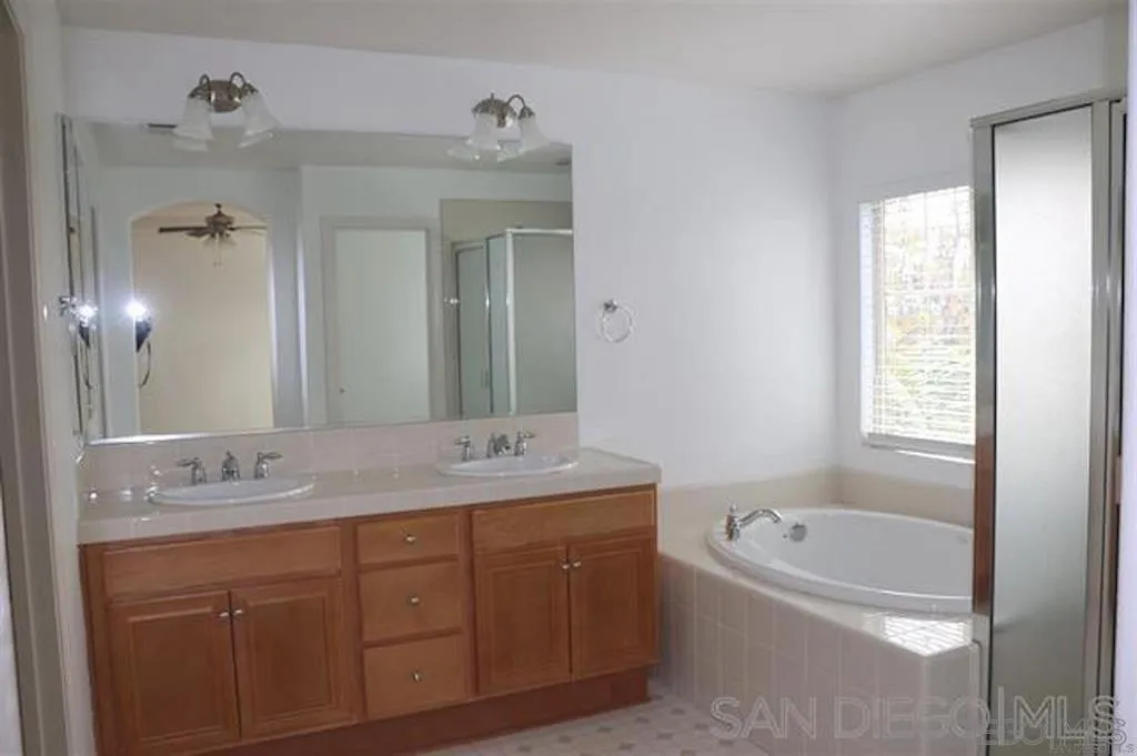 1586 Hopscotch Drive Chula Vista, CA 91915 - Photo 5 of 7 a bathroom with a granite countertop sink a mirror a bathtub and shower
