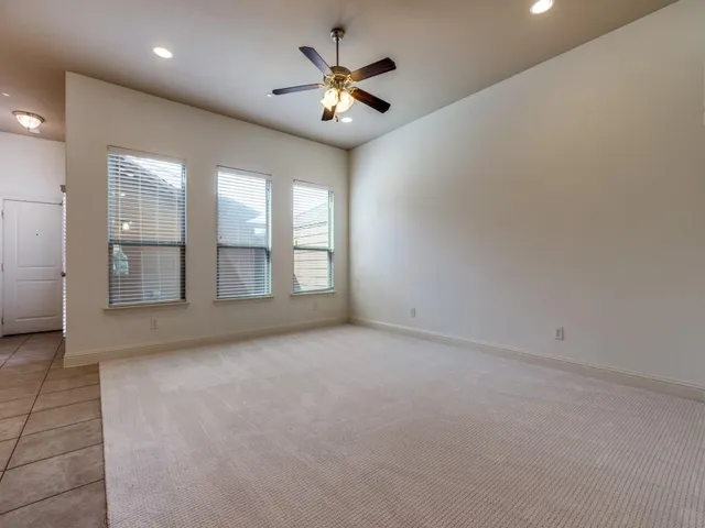an empty room with chandelier fan and windows