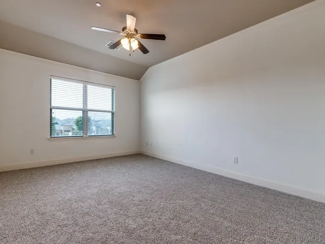 an empty room with windows and chandelier fan