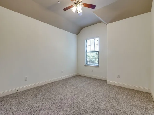 an empty room with a chandelier fan and windows