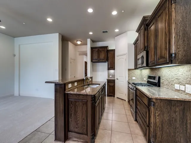 a kitchen with stainless steel appliances granite countertop a stove a sink and a refrigerator