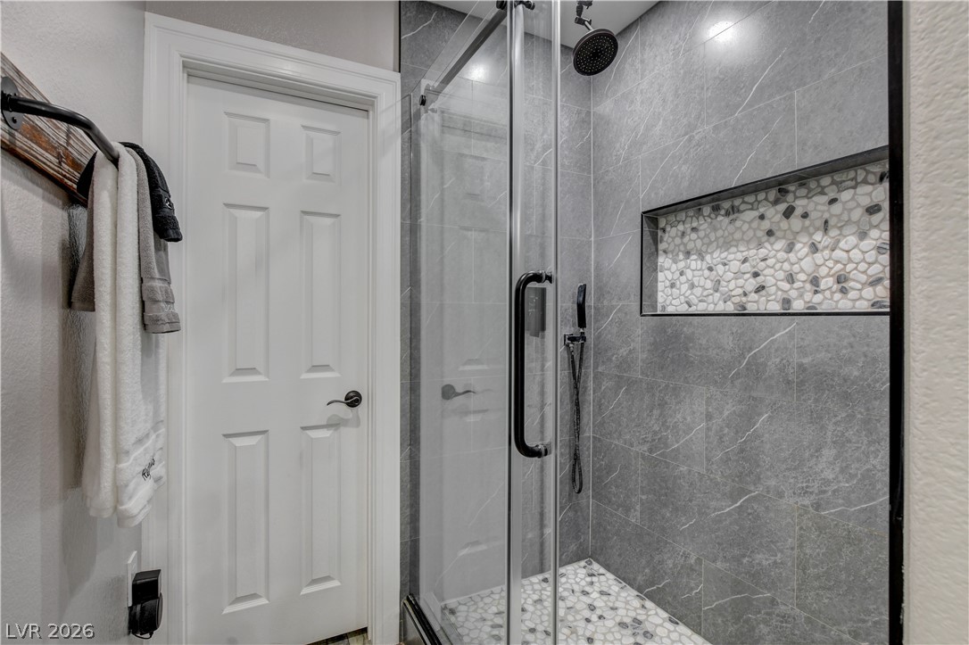 6460 Racel Street Las Vegas, NV 89131 - Photo 47 of 59 Textured tile and a glass door elevate the contemporary walk-in shower design.