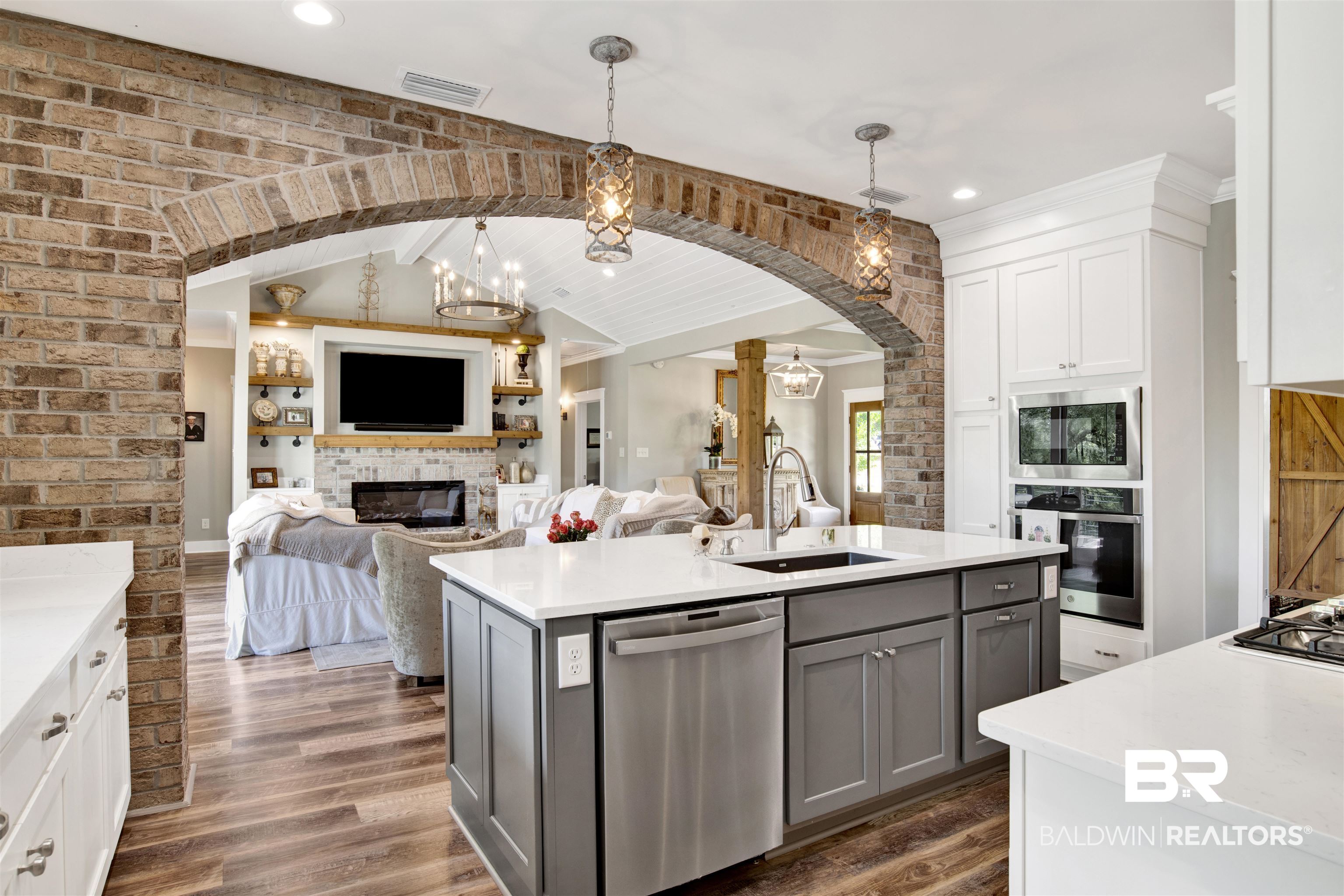 21621 Veranda Boulevard Fairhope, AL 36532 - Photo 25 of 51 Kitchen featuring gray cabinets, visible vents, a sink, a glass covered fireplace, and stainless steel appliances