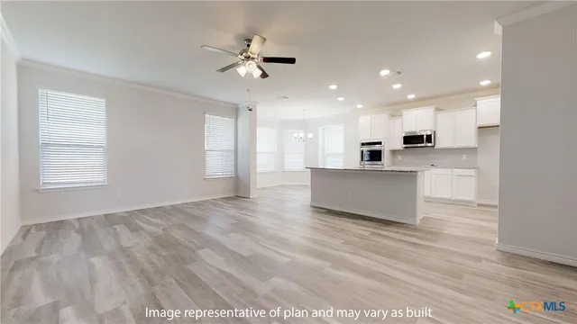 a view of a big room with wooden floor and a kitchen