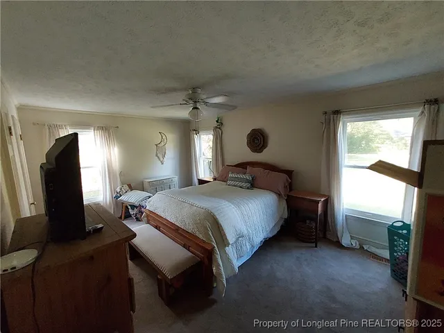 a spacious bedroom with a bed and a dresser next to a window