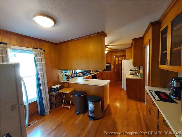 a kitchen with stainless steel appliances granite countertop a refrigerator a sink dishwasher a stove and white countertops with wooden floor