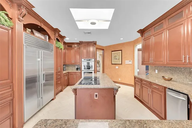 a large kitchen with kitchen island a large counter top appliances and cabinets