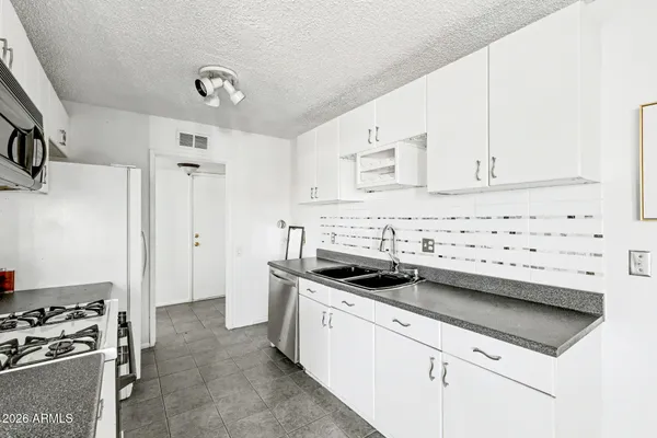 a kitchen with stainless steel appliances a stove a sink a refrigerator white cabinets and a refrigerator