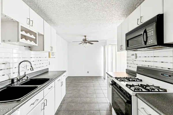 a kitchen with granite countertop a sink stove and refrigerator