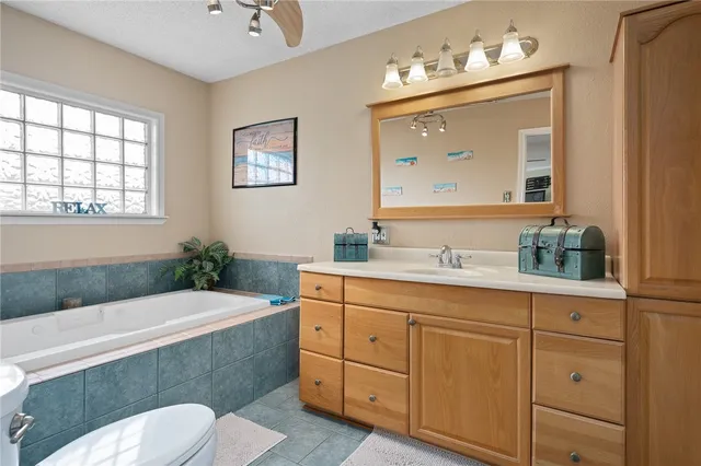 a bathroom with a granite countertop bathtub sink vanity mirror and toilet