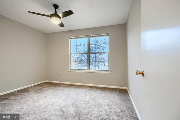 an empty room with a window and a fan