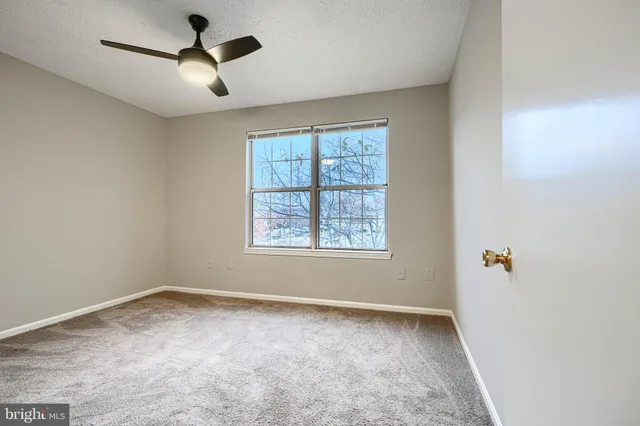 an empty room with a window and a fan