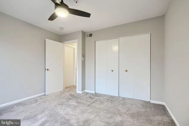 a view of an empty room and chandelier fan